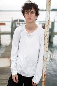 Portrait of young man standing against lake