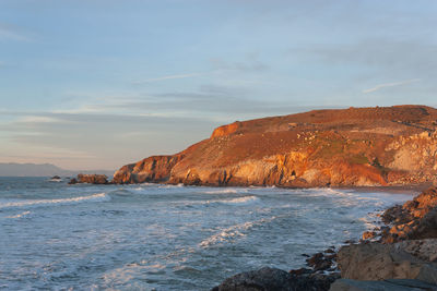 Rock formation on beach against sky