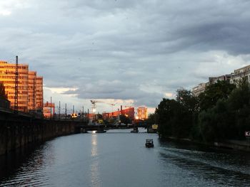 City at waterfront against cloudy sky