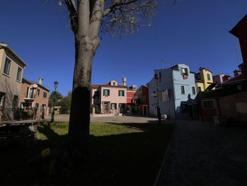 Street amidst buildings against clear blue sky