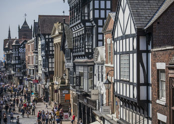 People on street amidst buildings in city of chester 