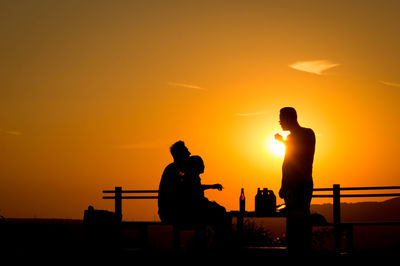 Silhouette man standing against orange sky during sunset