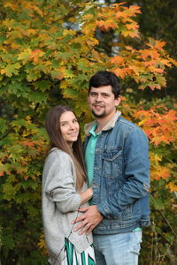 Portrait of smiling young couple standing against plants