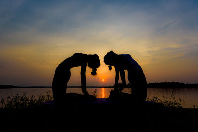 Silhouette men against orange sky during sunset
