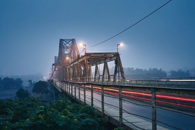 Light trails on bridge against sky