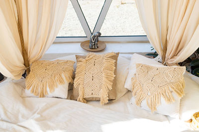 Beige macrame pillows and knit blanket on the sofa. scandinavian cozy home, details interior.