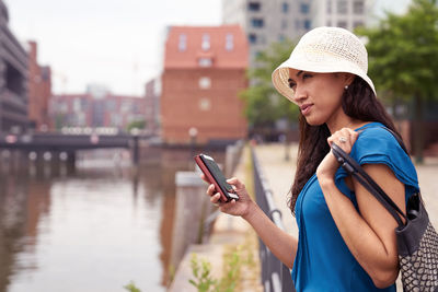 Side view of mid adult woman using mobile phone by river