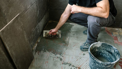 Low section of man applying cement on floor