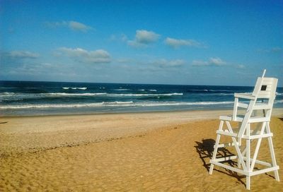 Lifeguard chair on beach against sky