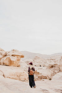 Young woman standing on desert against clear sky