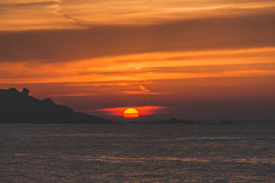 Scenic view of sea against cloudy sky during sunset