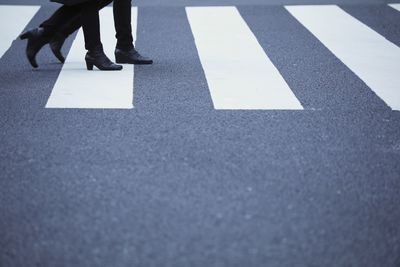 Low section of people walking on zebra crossing