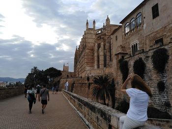 Rear view of people walking on historic building against sky