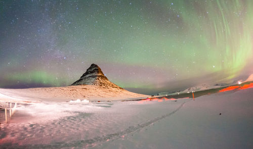 Scenic view of snow covered land against sky at night