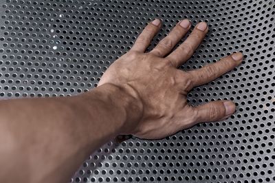 Cropped hand touching perforated metal
