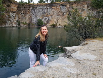 Portrait of smiling young woman standing on rock