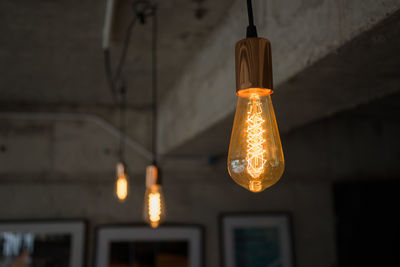 Low angle view of illuminated light bulbs hanging from ceiling