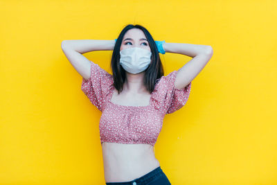 Beautiful young woman looking away against yellow background