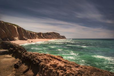 Scenic view of sea by mountains against sky