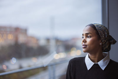 Young woman looking through window