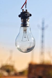 Close-up of light bulb hanging against sky