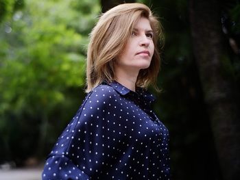 Thoughtful woman standing against trees