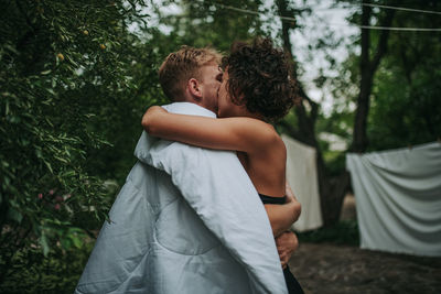 Rear view of couple kissing against trees