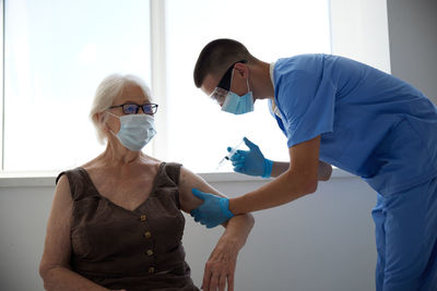 Doctor wearing mask vaccinating patient