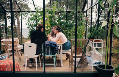 People sitting on chair by table against plants