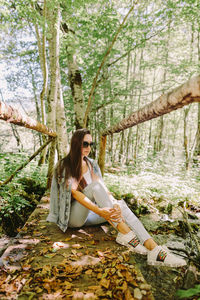 Full length of woman sitting in forest