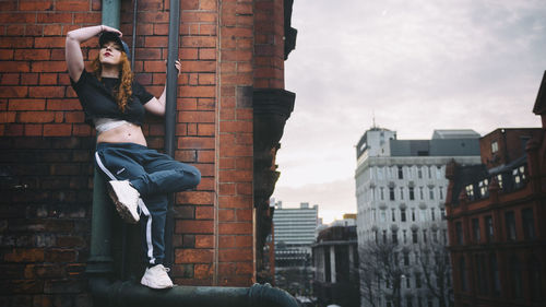 Low angle view of young woman against buildings in city