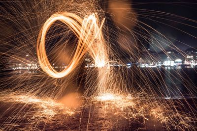Blurred motion of burning wire wool by lake at night