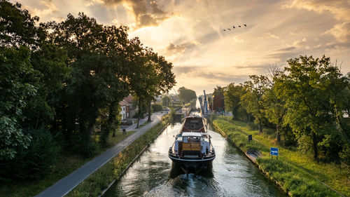 Aerial view of a colourful dramatic sunrise sky over a canal with a cargo boat in belgium. 