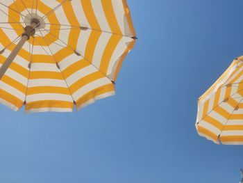 Low angle view of parasol against clear blue sky