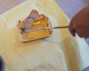 Paint brush dipping in gold paint in a plastic container. wall painting project.