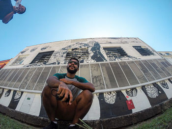 Young latino brazilian man posing to camera in front of famous wall graffiti in rio de janeiro