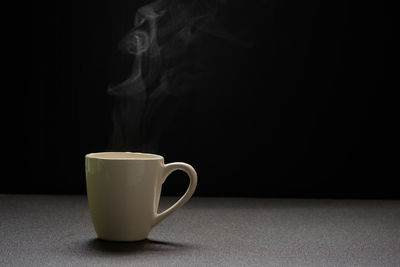 Close-up of coffee cup on table against black background