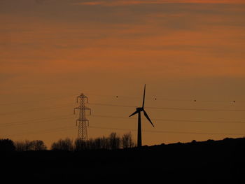 Silhouette wind turbines on field against sky during sunset