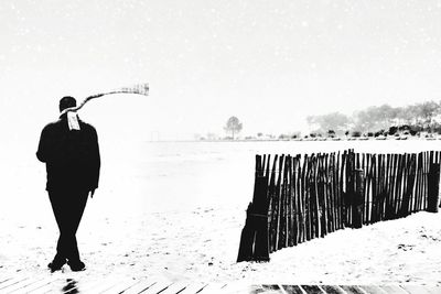 Man standing on snow covered beach against sky