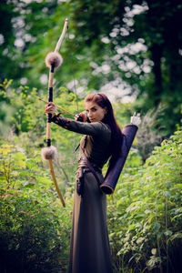 Full length portrait of woman standing against trees in forest