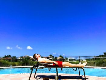 Young man in swimming pool against blue sky