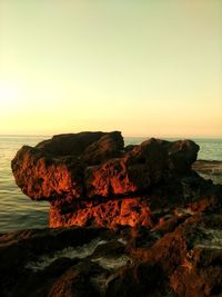 Rock formations by sea against clear sky