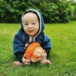 Portrait of a  baby boy holding a pumpkin on grass