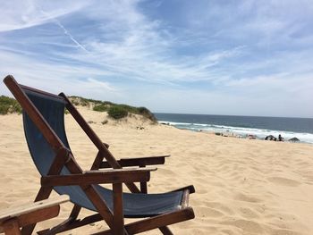 Chair on beach against sky