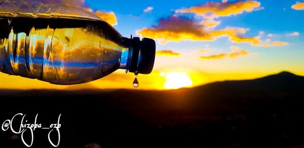 Close-up of camera on silhouette land against sky during sunset