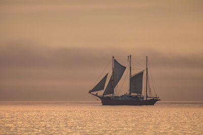 Sailboat sailing on sea against sky during sunset