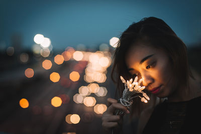 Woman holding illuminated lights at night