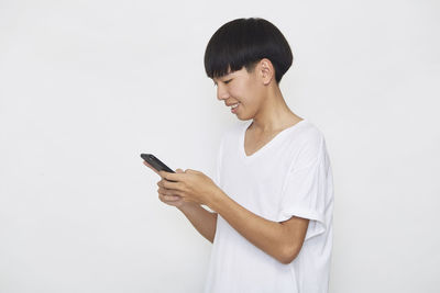 Young man using smart phone against white background