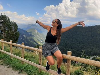 Full length of young woman standing on mountain against sky