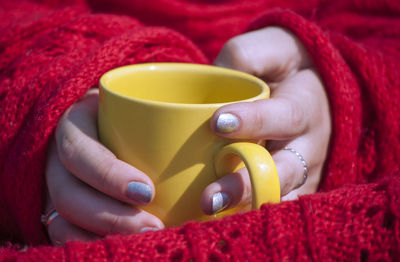 Close-up of woman holding tea cup on bed